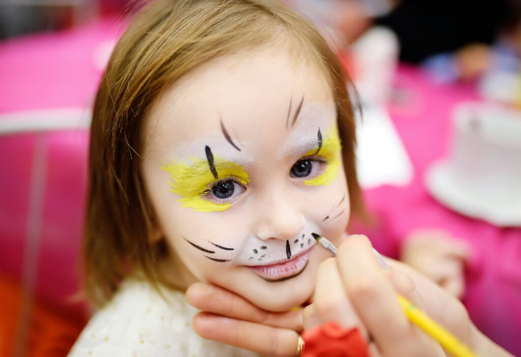 Face painting for cute little gorl during kids merriment. Face paint for "Animals" theme on party