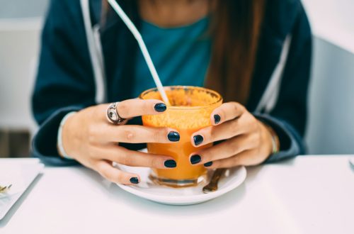 Close up on the hands of a young woman holding a glass of juice - health, break, relaxing concept